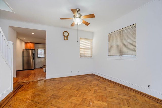 empty room featuring a ceiling fan, healthy amount of natural light, baseboards, and ornamental molding