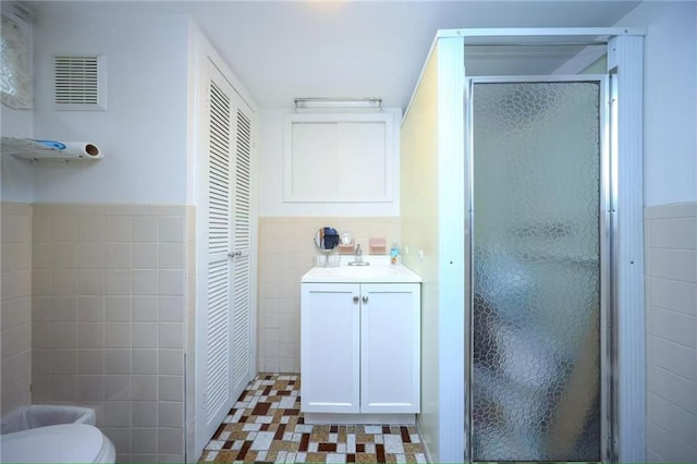 2961 Voorhies Ave, Brooklyn, NY 11235 - bathroom with tile walls, a stall shower, vanity, a closet, and wainscoting