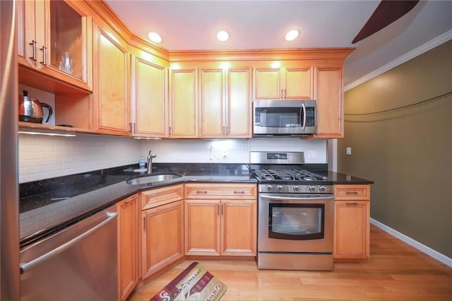 2961 Voorhies Ave, Brooklyn, NY 11235 - kitchen with appliances with stainless steel finishes, a sink, decorative backsplash, light wood-style flooring, and dark stone countertops