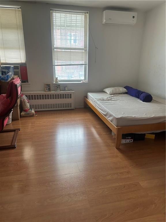 2878 W 16th St, Brooklyn, NY 11224 - bedroom featuring radiator heating unit, a wall mounted AC, wood finished floors, and cooling unit