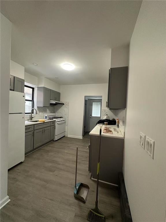 kitchen featuring gray cabinets, a sink, light countertops, baseboards, and white appliances