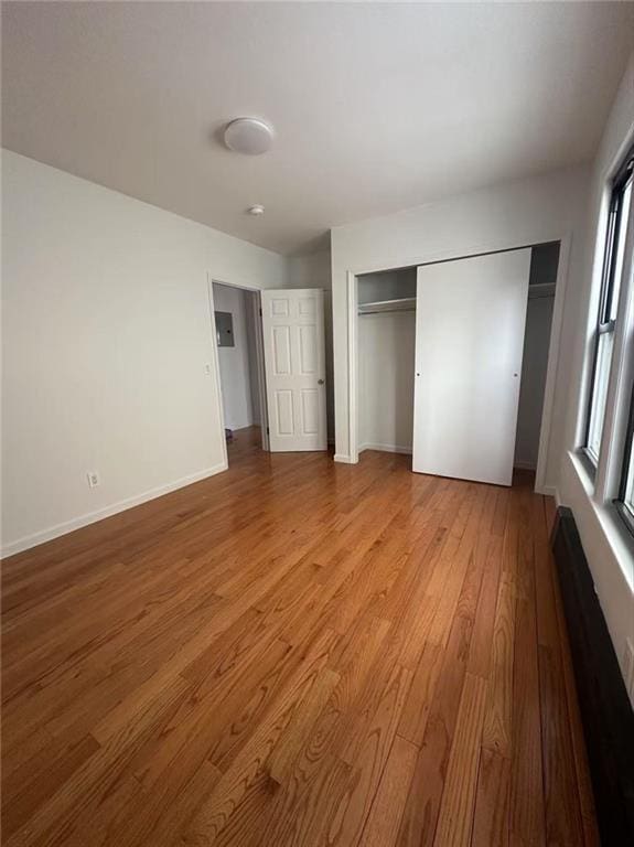 unfurnished bedroom with baseboards, wood finished floors, and a closet
