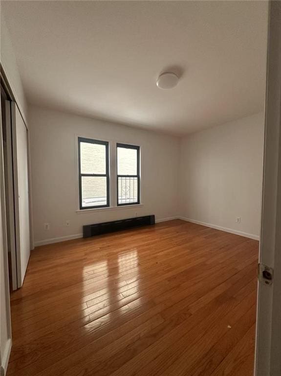unfurnished bedroom featuring baseboards, wood finished floors, and a closet
