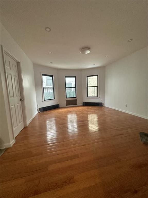 unfurnished room with baseboards, wood finished floors, and a wealth of natural light