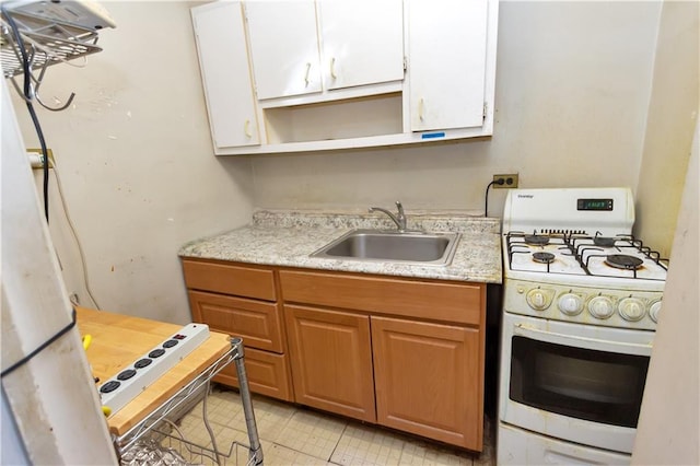kitchen with a sink, gas range gas stove, open shelves, and white cabinetry