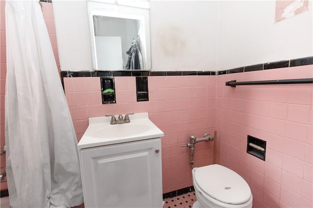 bathroom featuring tile walls, vanity, toilet, curtained shower, and wainscoting
