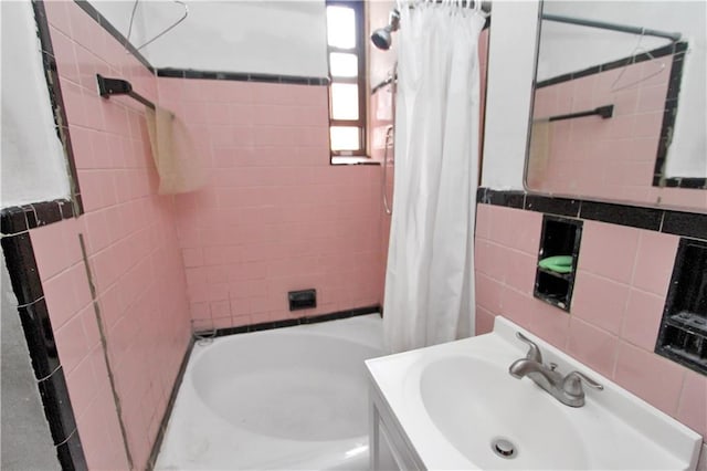 bathroom featuring tile walls, shower / bathtub combination with curtain, and vanity