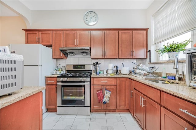 4715 Bedford Ave, Brooklyn, NY 11235 - kitchen with stainless steel gas range oven, under cabinet range hood, decorative backsplash, and light stone counters