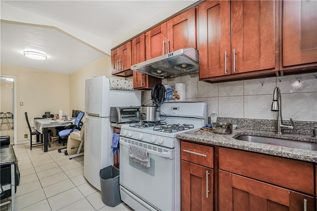 4715 Bedford Ave, Brooklyn, NY 11235 - kitchen featuring white range with gas stovetop, under cabinet range hood, light tile patterned flooring, dark stone counters, and tasteful backsplash