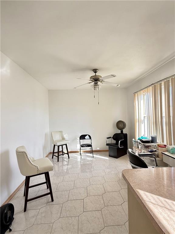 living area with ceiling fan and baseboards