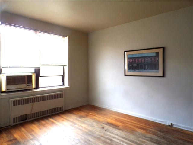 unfurnished room with wood finished floors and radiator heating unit