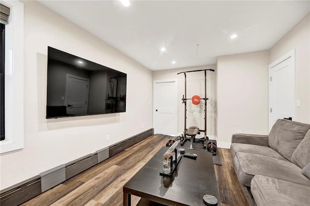 exercise area featuring recessed lighting, baseboards, a baseboard heating unit, and wood finished floors
