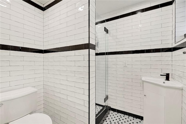 bathroom with a sink, a shower stall, toilet, and tile walls