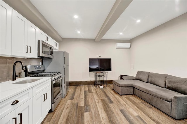 kitchen with appliances with stainless steel finishes, light wood-type flooring, a sink, open floor plan, and recessed lighting