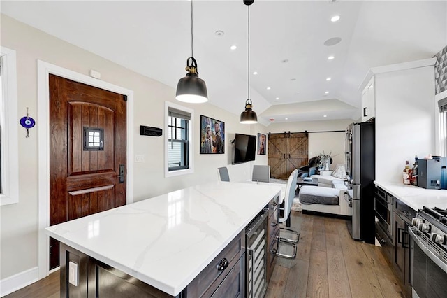 kitchen with open floor plan, dark wood finished floors, appliances with stainless steel finishes, and a barn door