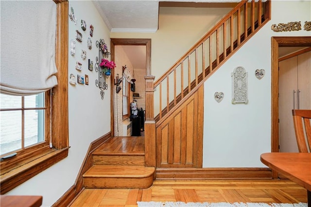 stairway with crown molding, wood finished floors, and baseboards