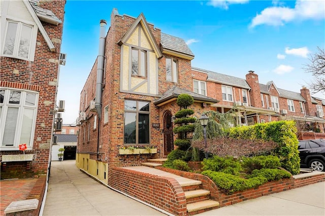 tudor-style house with brick siding, a residential view, and a high end roof