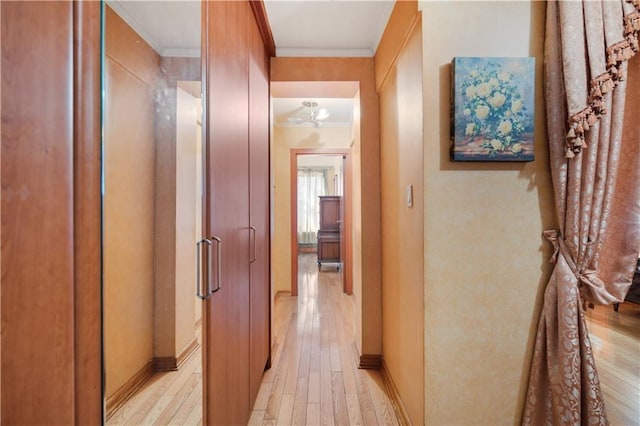 hall with baseboards, ornamental molding, and light wood-type flooring