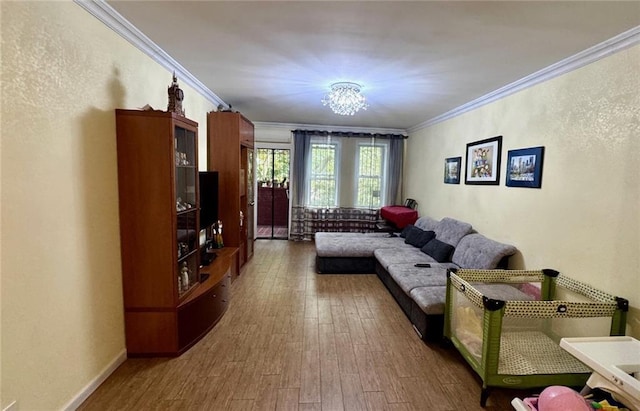 living area with ornamental molding, wood finished floors, and a chandelier
