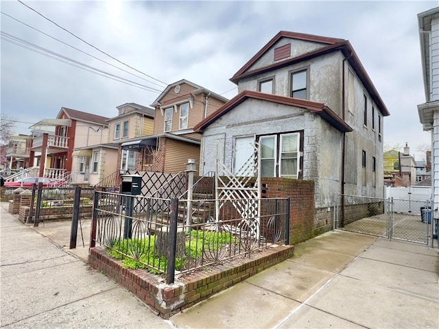 view of front of home with fence, a residential view, stucco siding, and a gate