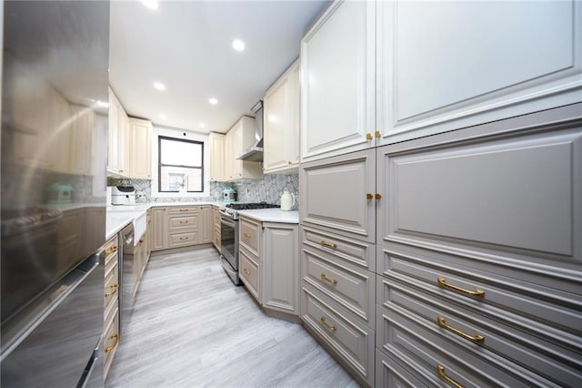 kitchen with backsplash, gray cabinetry, appliances with stainless steel finishes, and wall chimney range hood