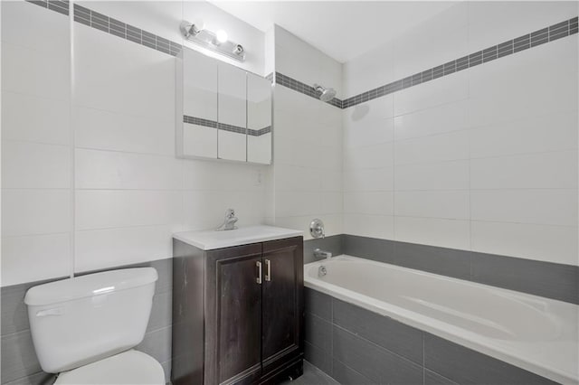 full bath with toilet, tiled shower / bath, tile walls, and vanity