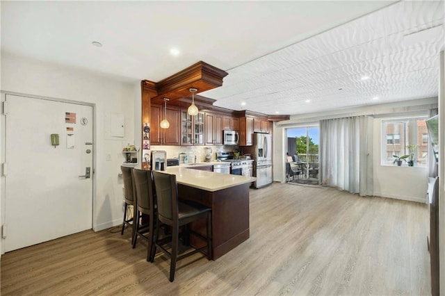 2752 Ocean Ave Unit 6A, Brooklyn, NY 11229 - kitchen featuring appliances with stainless steel finishes, light countertops, light wood finished floors, a peninsula, and glass insert cabinets