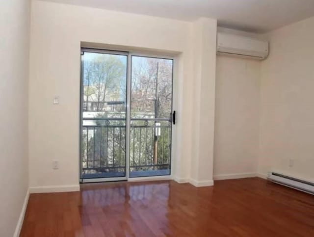 unfurnished room with baseboards, a baseboard radiator, wood finished floors, and a wall mounted air conditioner