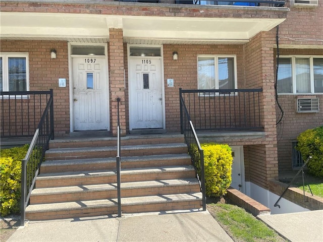 view of exterior entry featuring a porch and brick siding