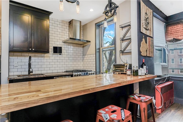 9707 4th Ave Unit 4P, Brooklyn, NY 11209 - kitchen featuring wooden counters, wall chimney exhaust hood, wood finished floors, backsplash, and a breakfast bar