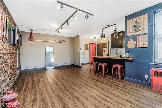 interior space with rail lighting, baseboards, wood finished floors, and a sink