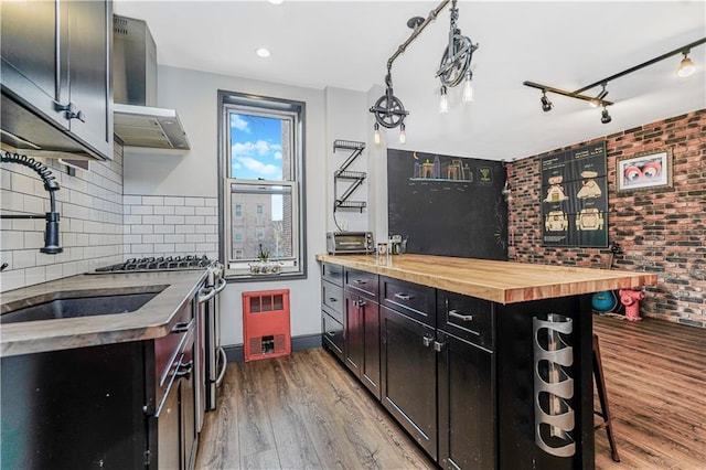 9707 4th Ave Unit 4P, Brooklyn, NY 11209 - kitchen featuring wooden counters, wall chimney exhaust hood, dark cabinetry, wood finished floors, and brick wall