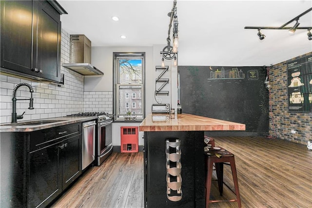 9707 4th Ave Unit 4P, Brooklyn, NY 11209 - kitchen featuring appliances with stainless steel finishes, wall chimney range hood, wooden counters, wood finished floors, and dark cabinetry