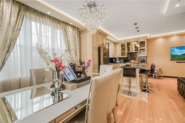 45 Oceana Dr E Unit 4B, Brooklyn, NY 11235 - kitchen featuring wall chimney range hood, cream cabinetry, a chandelier, glass insert cabinets, and light wood finished floors