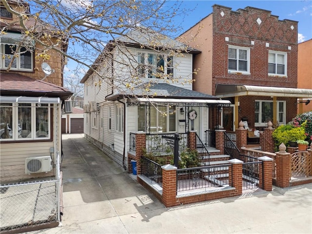 view of front of property featuring a fenced front yard, ac unit, an outbuilding, a garage, and brick siding