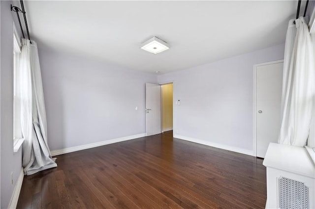 spare room with baseboards and wood finished floors