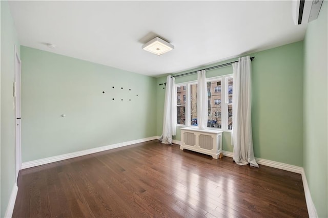 empty room featuring baseboards, radiator heating unit, and wood finished floors