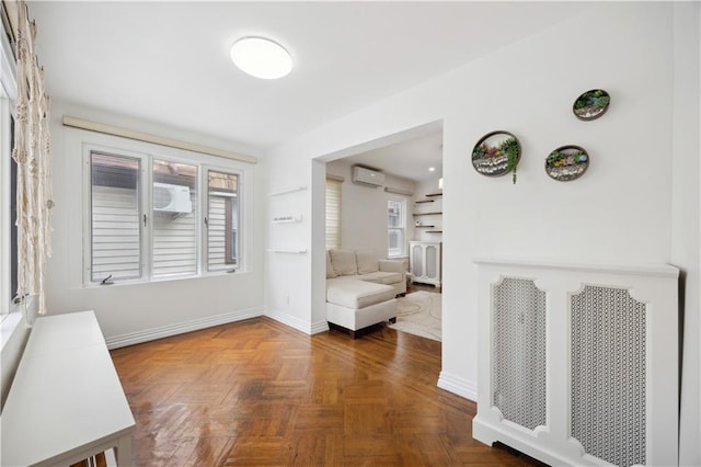hallway featuring baseboards, a wall mounted AC, and a wealth of natural light