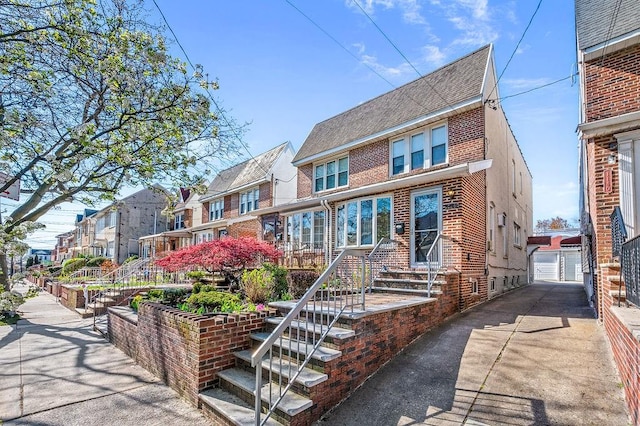 view of front of property featuring brick siding, roof with shingles, a residential view, and a detached garage