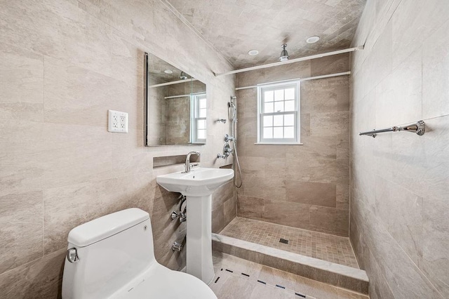 bathroom with tiled shower, toilet, and tile walls