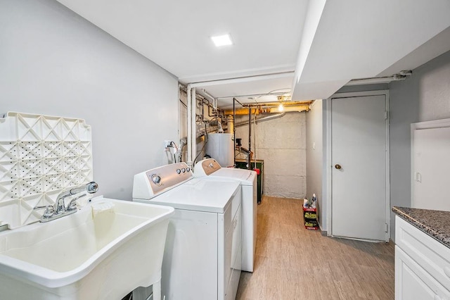 washroom featuring a sink, gas water heater, washing machine and clothes dryer, and light wood finished floors