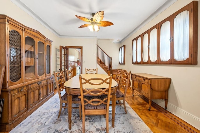 dining room featuring ceiling fan, baseboards, and stairway