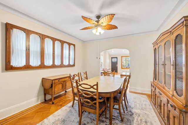 dining room with arched walkways, ceiling fan, and baseboards
