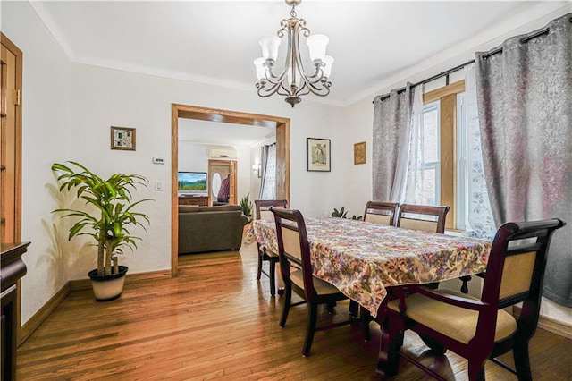 dining area featuring a chandelier, wood finished floors, and baseboards