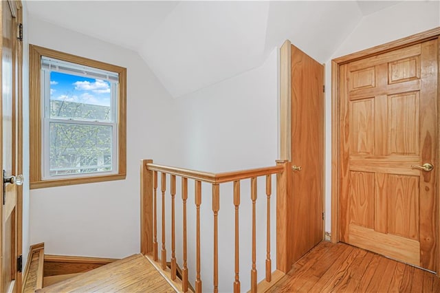 hall featuring vaulted ceiling, hardwood / wood-style flooring, and an upstairs landing