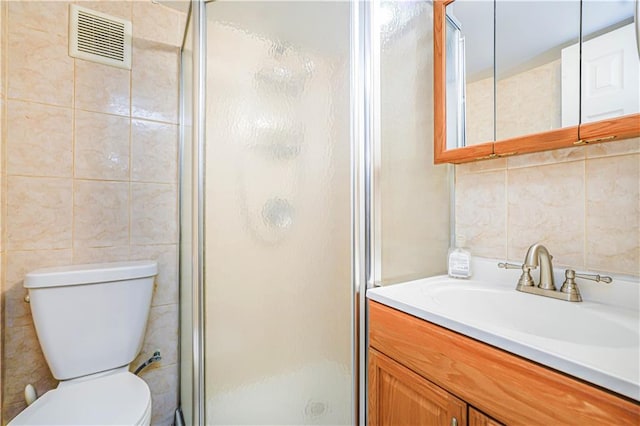 bathroom featuring tile walls, a shower stall, toilet, and vanity