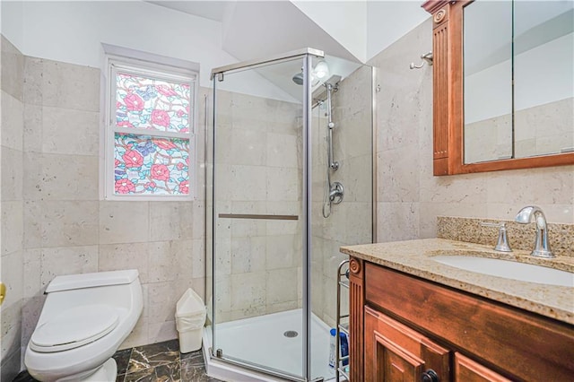 bathroom featuring tile walls, a shower stall, toilet, vanity, and marble finish floors