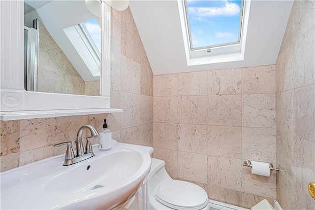 bathroom with a skylight, tile walls, lofted ceiling, toilet, and vanity