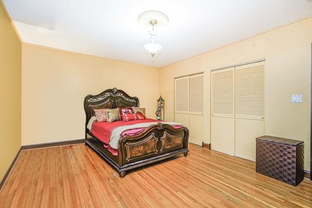 bedroom with wood finished floors, multiple closets, and baseboards
