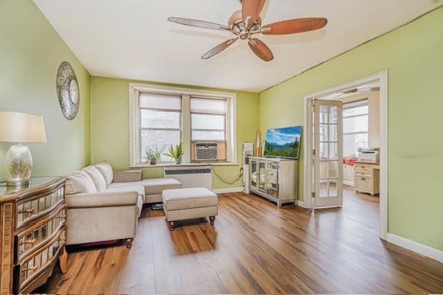 living room featuring radiator, wood finished floors, a ceiling fan, and baseboards